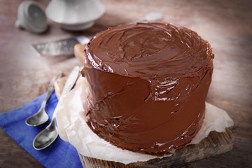 Chocolate cake with two spoons and blue tablecloth on a wooden boards background