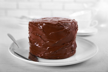 Chocolate cake on a plate with blade on light background