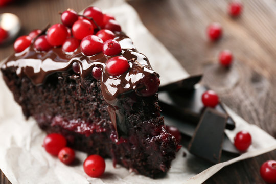 Piece of chocolate cake with cranberries on parchment, closeup