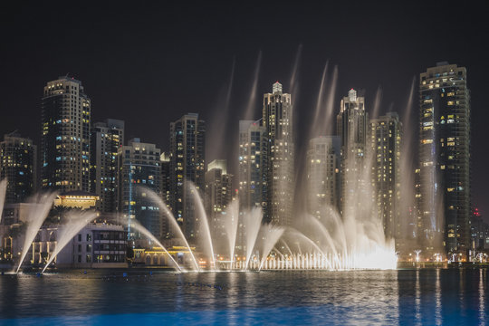 UAE, Dubai, view to skyline by night with trick fountains in the foreground