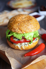 Big tasty hamburger with chili on paper, close up