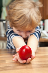 Red Easter egg in hand of a child.