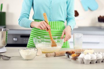 Obraz na płótnie Canvas Young woman mixing dough in a bowl