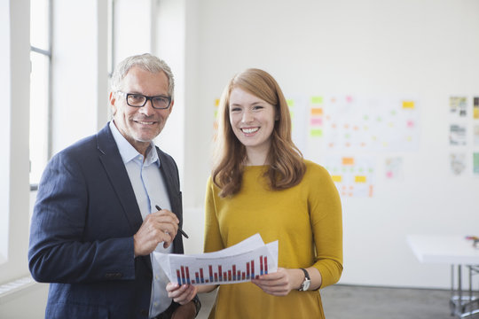 Businessman and coworker in office studying infographics