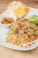 fried rice with vegetables, meat and fried eggs served on a plate with chopsticks