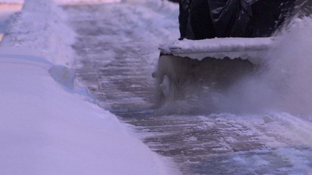Snow removal with snow blower from pavement in flat house yard parking. Static closeup shot. 4K
