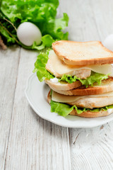 
sandwich with chicken breast , egg, lettuce, cheese and mayonnaise on a wooden background