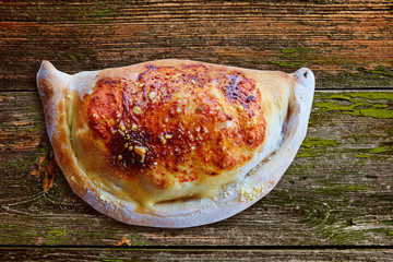 Pizza Calzone folded as a patty on a wooden