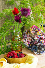 Fototapeta na wymiar букет садовых цветов маков и ягоды в деревянной тарелке
