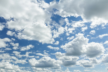 Obraz premium White clouds in blue sunny sky with sun backlight