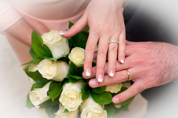 Hands with wedding rings and bridal bouquet