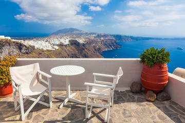 Table and chairs on roof with a panorama view on Santorini island, Greece.
