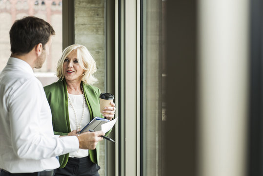 Portrait of smiling blond businesswoman communicating with a colleague