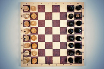 Wooden chess on blue gradient background. Flat lay view. Vintage toning.