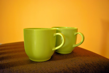 Two coffee cups on the chair with yellow wall background 