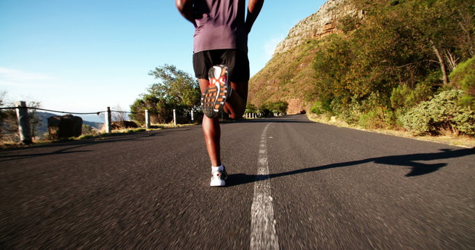 Jogger running along mountain road in slow motion
