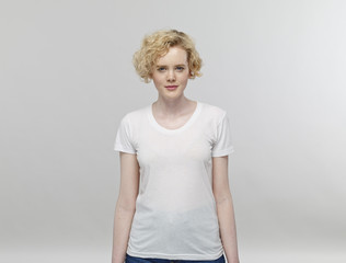 Portrait of blond woman wearing white t-shirt in front of grey background