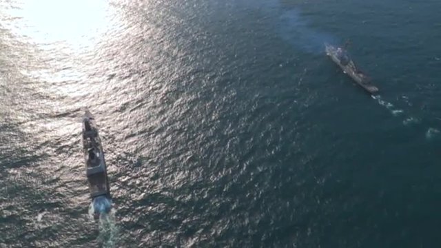 Aerials over an aircraft carrier and strike group on the high seas.