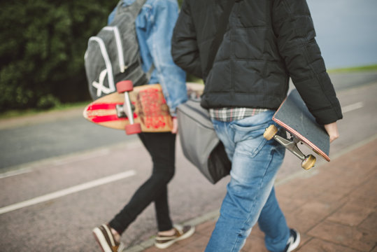 Back View Of Two Walking Skaters With Longboard And Skateboard