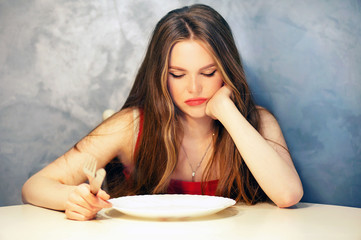 Hungry young woman waiting with an empty plate.