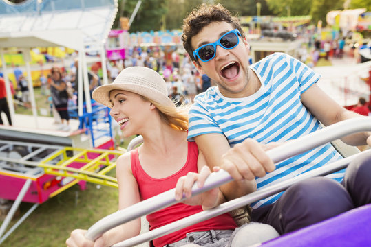 Happy couple at fun fair riding roller coaster