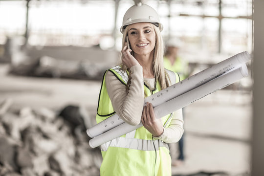 Woman in protective workwear on cell phone in construction site