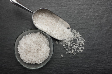 metal scoop full of white salt in a glass bowl