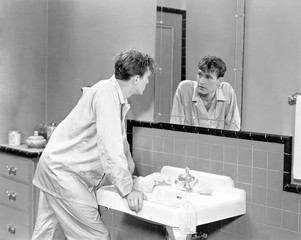 Man in bathroom looking into mirror 