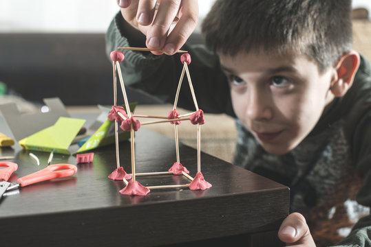 Boy building a house with modeling clay and toothpicks