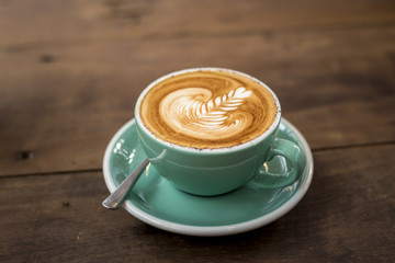 hot cappuccino with latte art on wood background