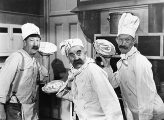 Papier Peint photo Lavable Rétro Three chefs holding pies for a fight in the kitchen 