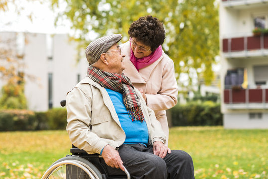 Senior woman looking at husband in wheelchair