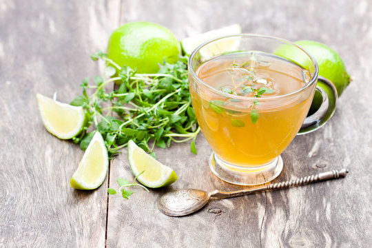 Green  tea with thyme and lime on rustic wooden background