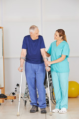 Alter Mann auf Krücken bei Physiotherapie