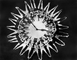 Female dancers circling huge clock 