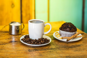 Cup of coffee served with coffee beans around.