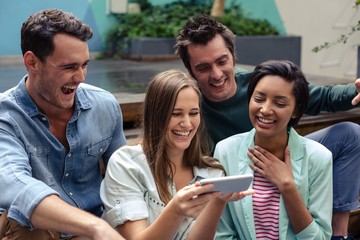 Happy friends using smartphone outside the bar