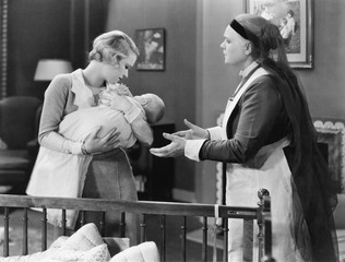 Mother giving her sleeping baby to a nanny 