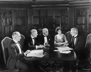 Group of men sitting with a young woman in a boardroom 