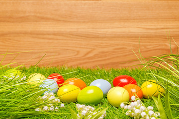 Naklejka na ściany i meble Spring flowers and colorful easter eggs in front of wood