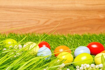 Spring flowers and colorful easter eggs in front of wood