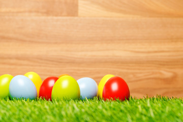 Easter eggs on grass with wood background