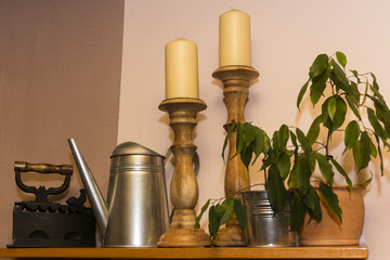 Obraz na płótnie Canvas ancient irons, kettles, candles and decorative ficus plant on the shelf