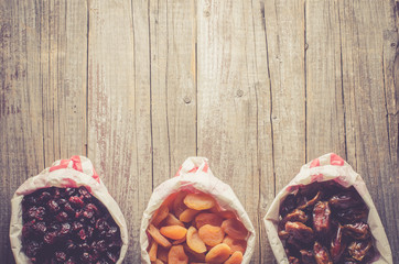 Overhead shot of dried fruits in paper bag on wooden table