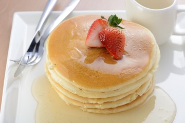 Stack of delicious pancakes with honey on plate isolated on white