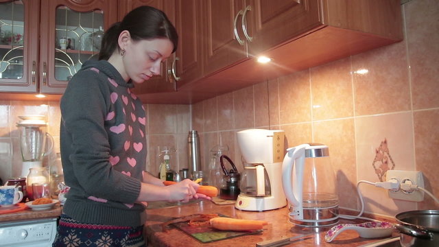 Girl in jamper cleaning carrot, knife