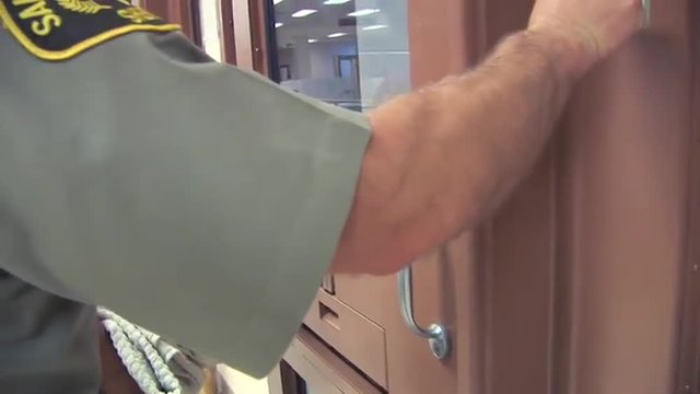 A suspect is booked into jail and an officer closes the door behind him.