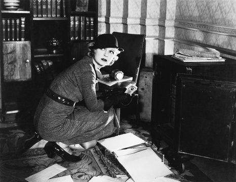 Young woman in an office next to a safe, looking over her shoulder 