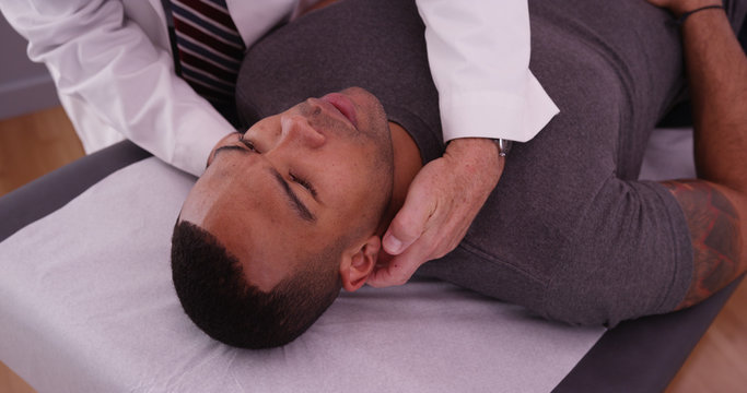 African-american male patient having neck pain examined by chiro