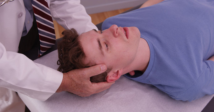 Young adult male having neck injury examined by chiropractor